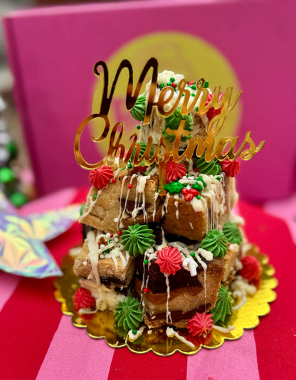 Decorative cake with 'Merry Christmas' topper on a striped pink and red background